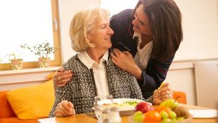 Eine Frau kümmert sich um eine ältere Frau, dass diese mit Essen versorgt wird.