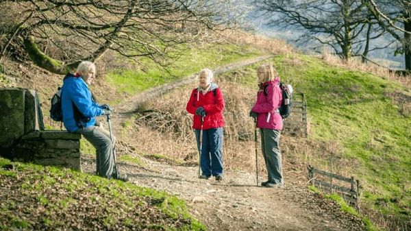 Drei Senioren machen eine Pause während des Wanderns. 