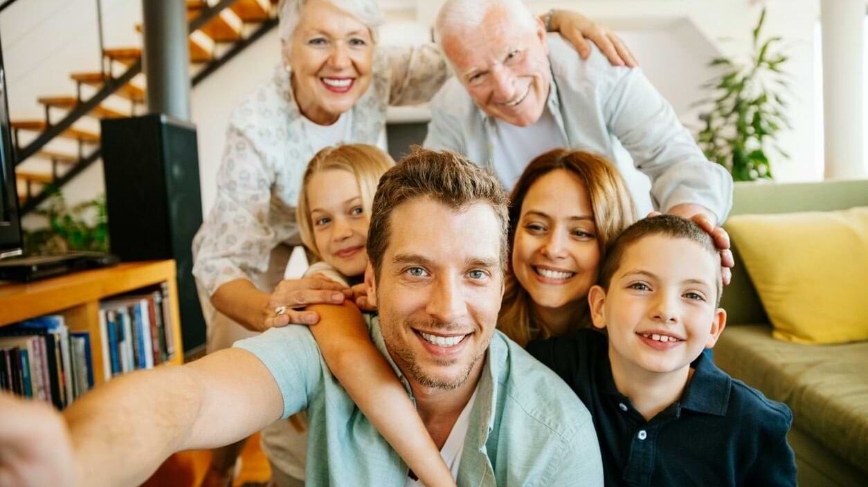 Familie mit mehreren Generationen macht ein Selfie im Wohnzimmer.