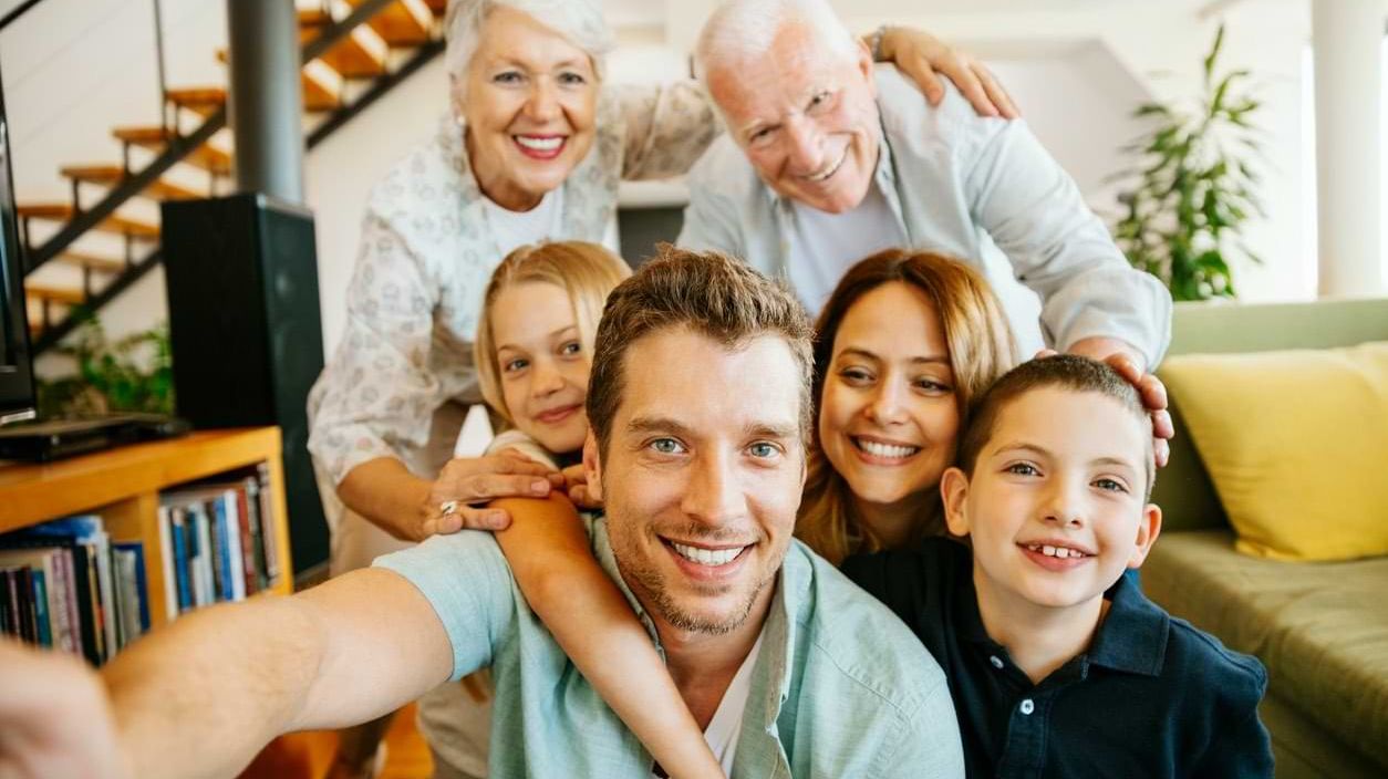 Familie mit mehreren Generationen macht ein Selfie im Wohnzimmer.