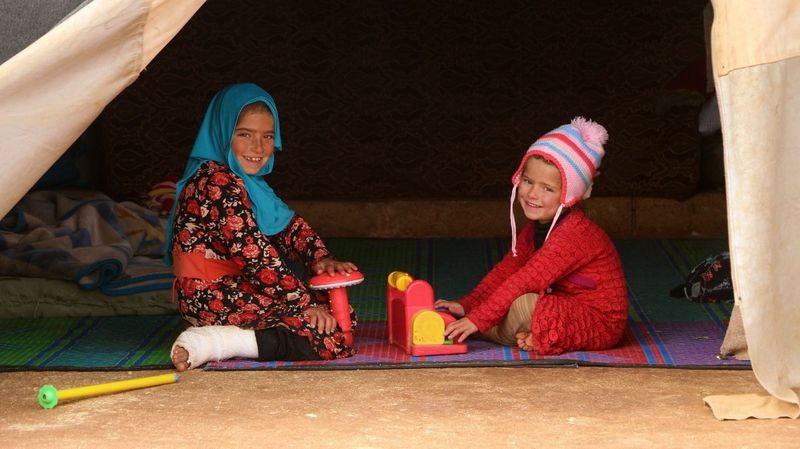 Kinder mit Spielzeug in einer Zeltunterkunft.