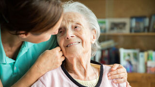 Alte Frau wird von Pflegekraft umsorgt. 