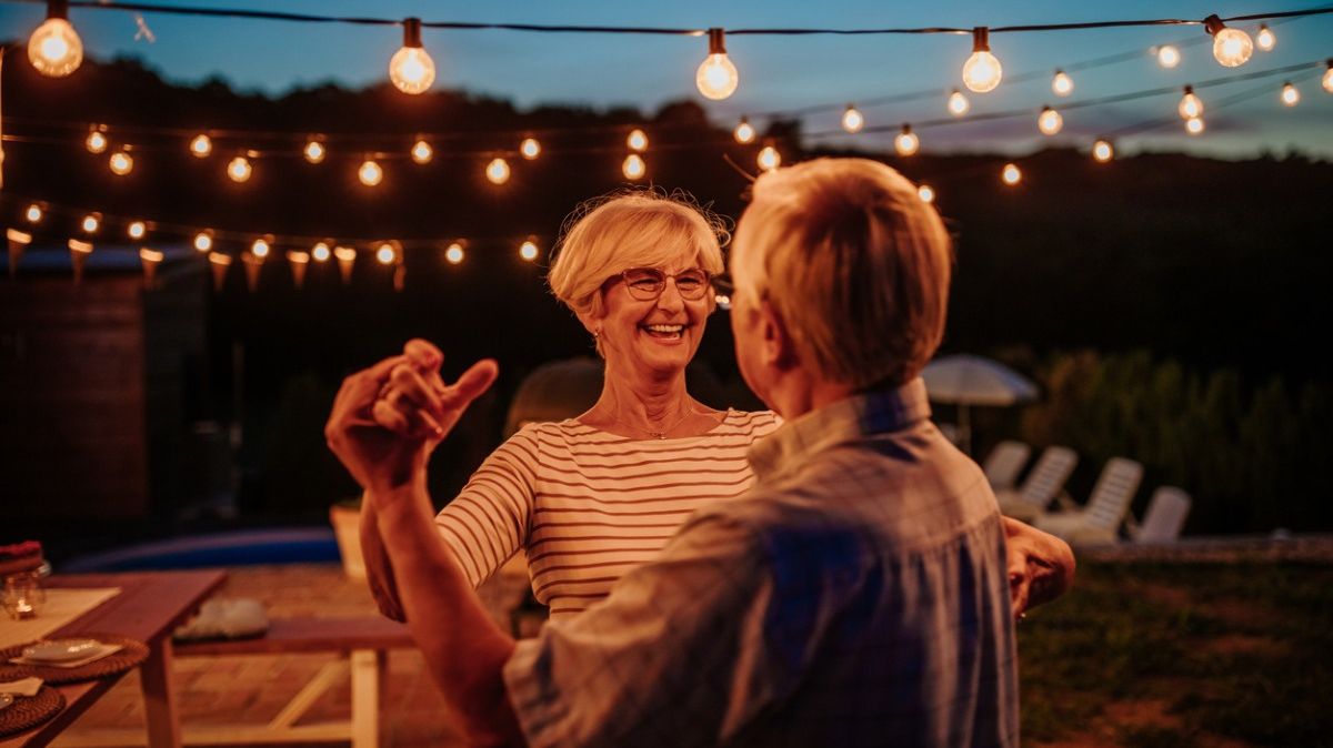 Ein Seniorenpaar tanzt im Freien unter Lampenlicht