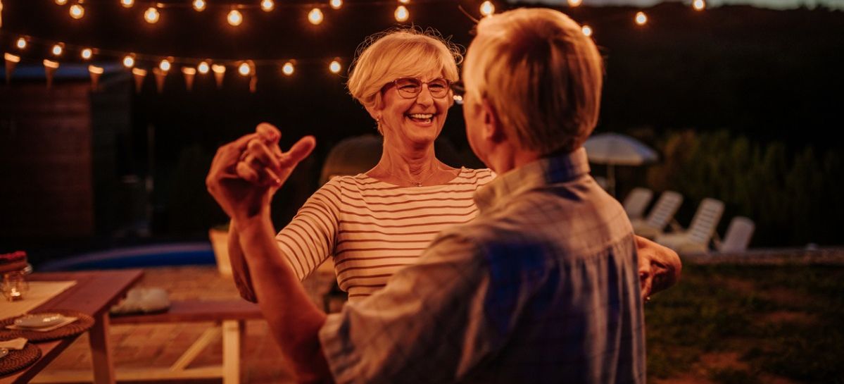 Ein Seniorenpaar tanzt im Freien unter Lampenlicht