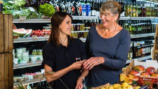 Eine Einkaufshilfe der Malteser hilft einer Frau beim einkaufen im Supermarkt.