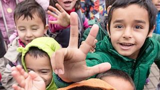 Es werden Flüchtlingskinder gezeigt, welche in die Kamera lachen.
