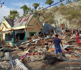 Überlebende in Indonesien stehen in den Trümmern, die das Erdbeben und der folgende Tsunami angerichtet haben. Foto: World Vision