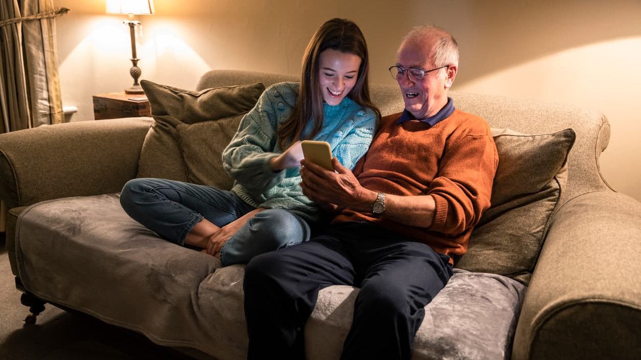 Älterer Mann und junge Frau betrachten Smartphone.