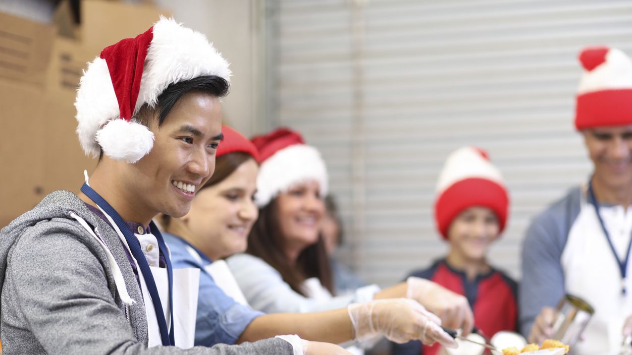 Menschen mit Weihnachtsmützen geben Essen an Bedürftige aus