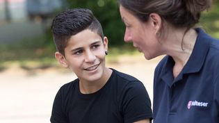 Eine junge Malteser Integrationslotsin unterhält sich mit einem Jungen.