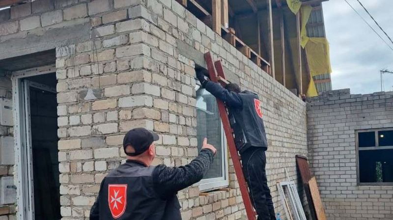 Zwei Männer setzen ein neues Fenster in ein Haus ein.