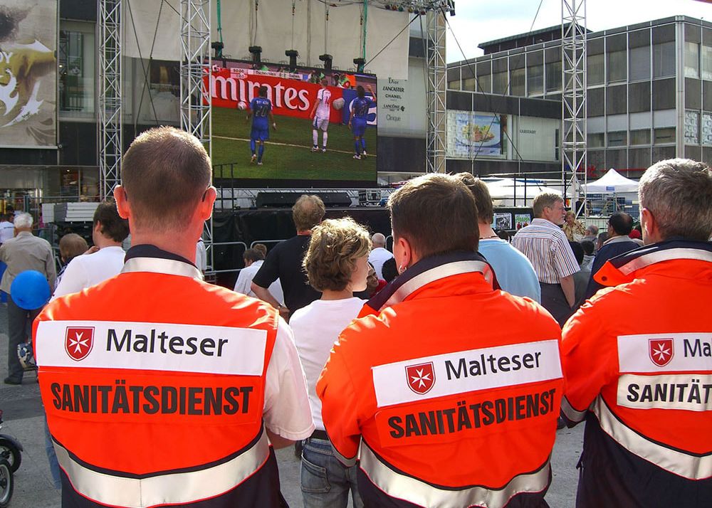 2006: Bei der Fußball-Weltmeisterschaft in Deutschland sind die Malteser mit fast 500 Ärzten und mehr als 14.200 ehrenamtlichen Helfenden für den Sanitäts- und Rettungsdienst an allen Spielstätten im Einsatz und in Bereitschaft.