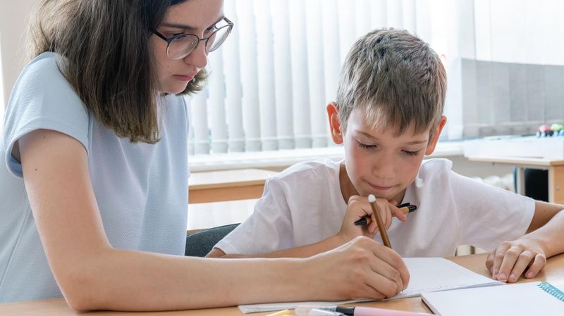 Eine Teenagerin mit Brille hilft einem Jungen bei den Hausaufgaben