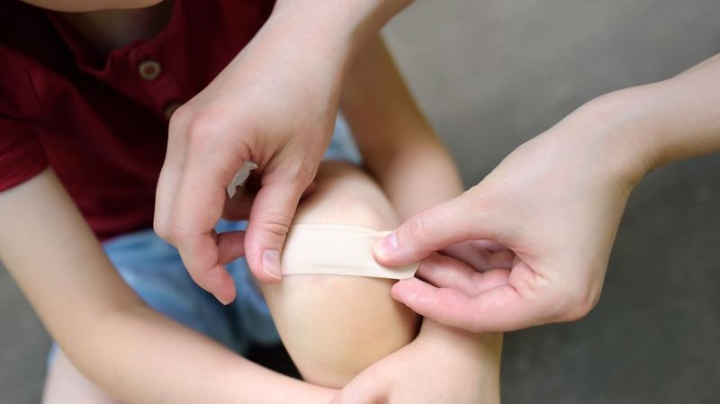 Knie eines kleinen Jungen wird mit einem Pflaster verarztet.
