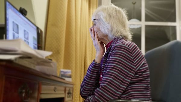 Eine bestürzt schauende ältere Frau vor einem Computermonitor. 