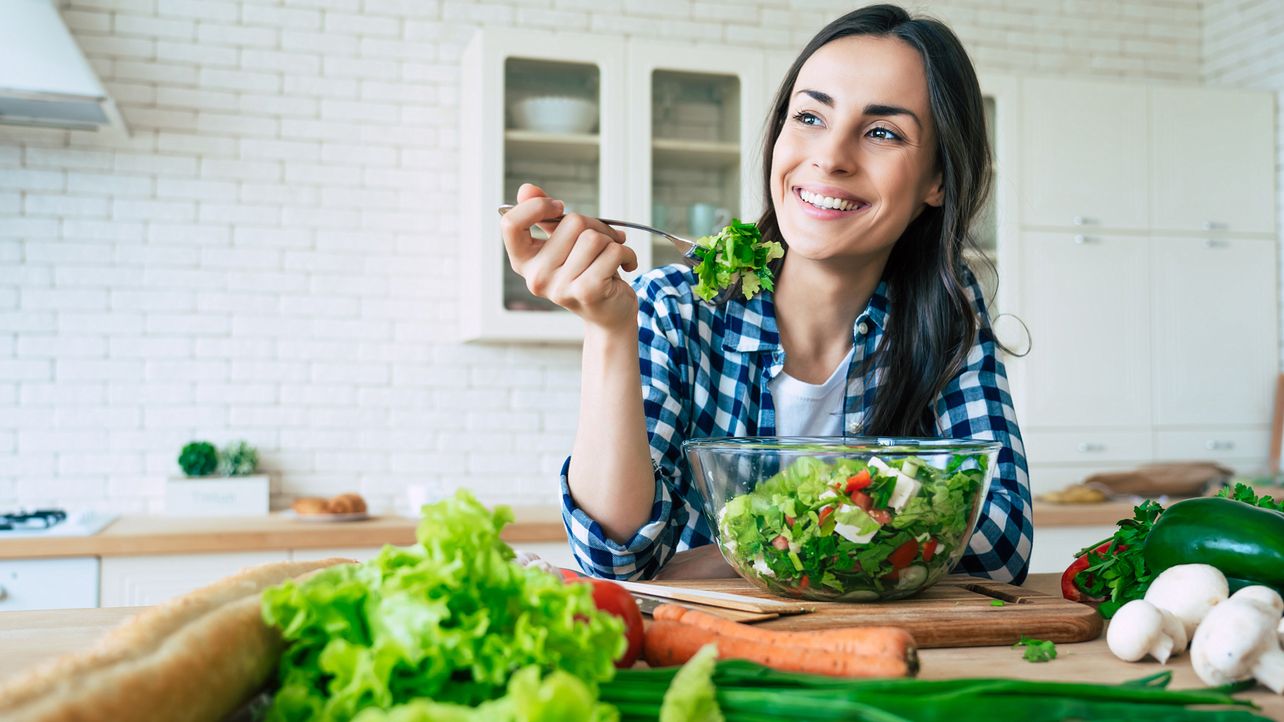 Lächelnde Frau isst aus einer Salatschüssel