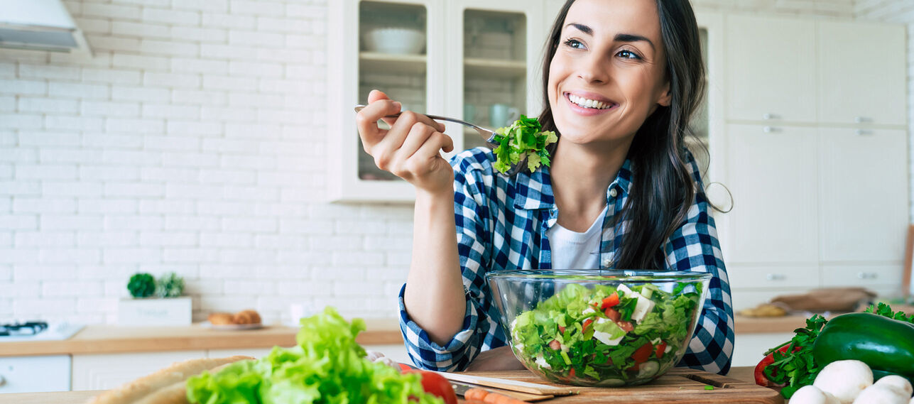 Lächelnde Frau isst Salat