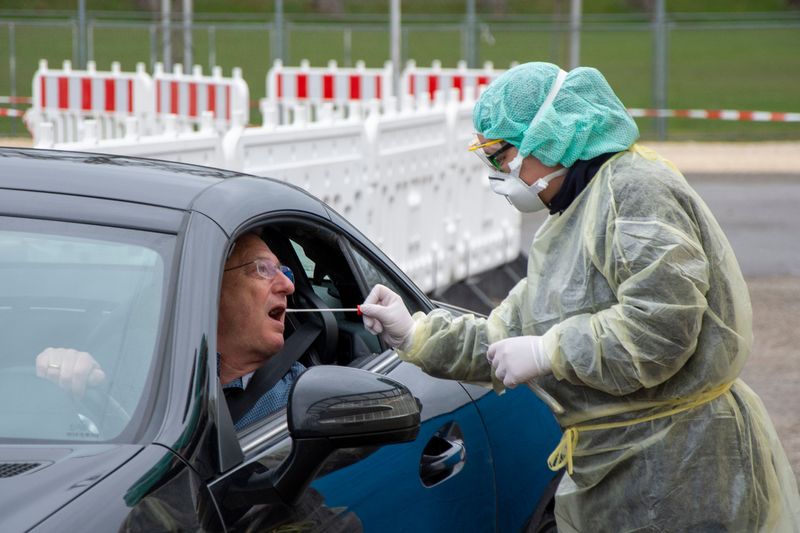 Eine Helferin der Malteser nimmt während einer Autokontrolle einen Rachenabstrich bei einem Mann.