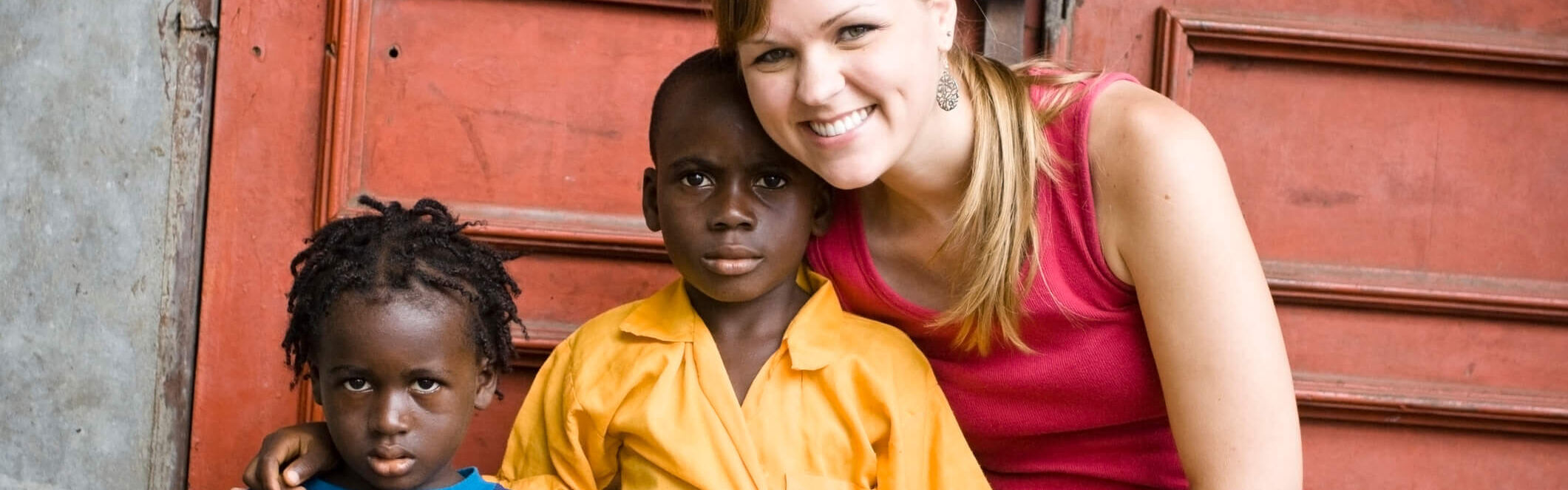 Junge europäische Frau posiert mit zwei afrikanischen Kindern