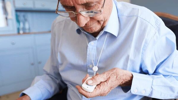 Der Malteser Hausnotruf Knopf wird von einem älteren Mann gedrückt.