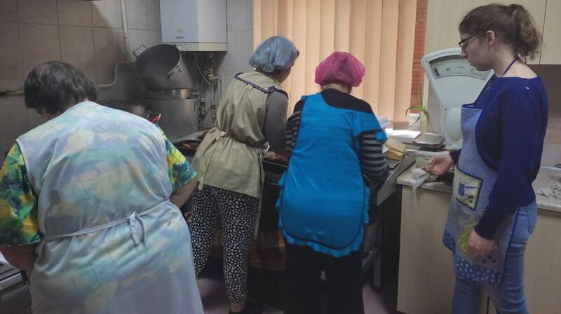 Vier Frauen mit Schürzen in einer Küche.