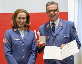 Links steht Sophie von Preysing und neben ihr Martin Rösler mit seiner Verdienstplakette und Urkunde in den Händen. Beide tragen Malteser Dienstbekleidung.