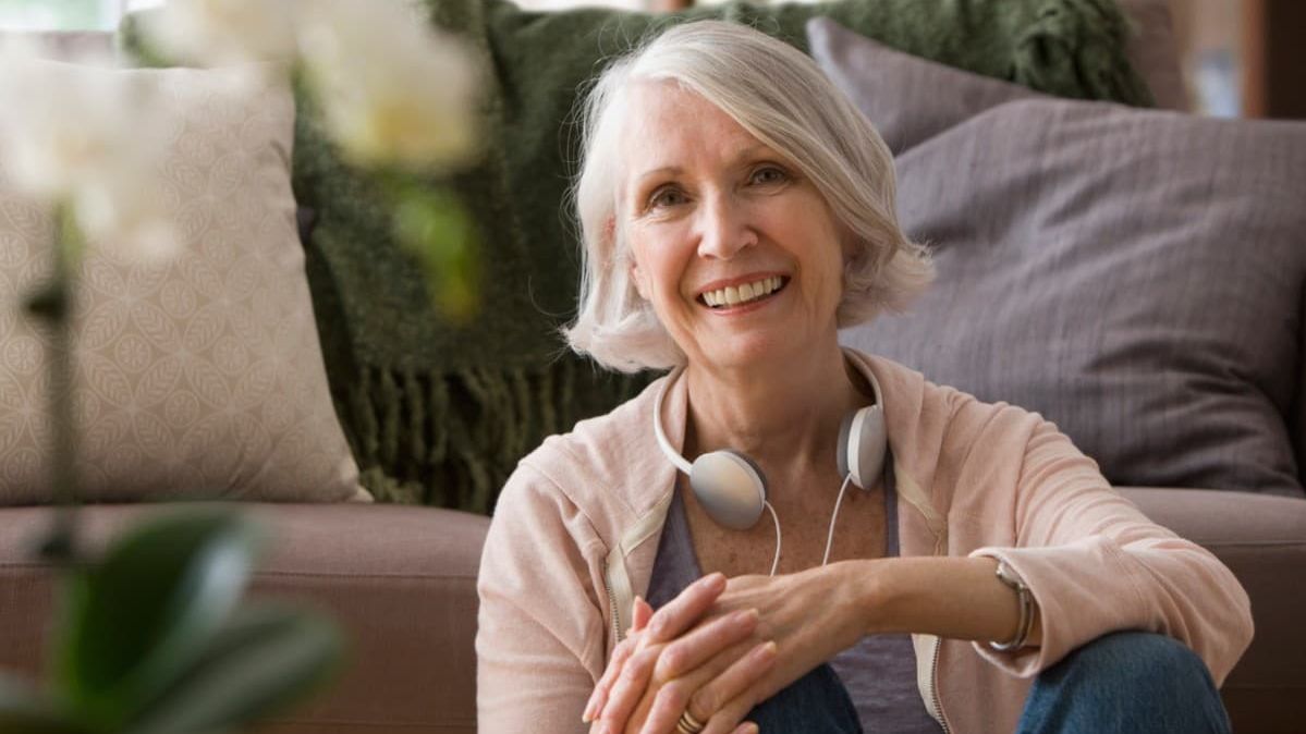 Ältere, lächelnde Frau mit Kopfhörern