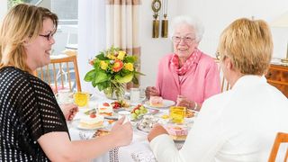 Drei Frauen sitzen am Tisch und essen Kuchen.