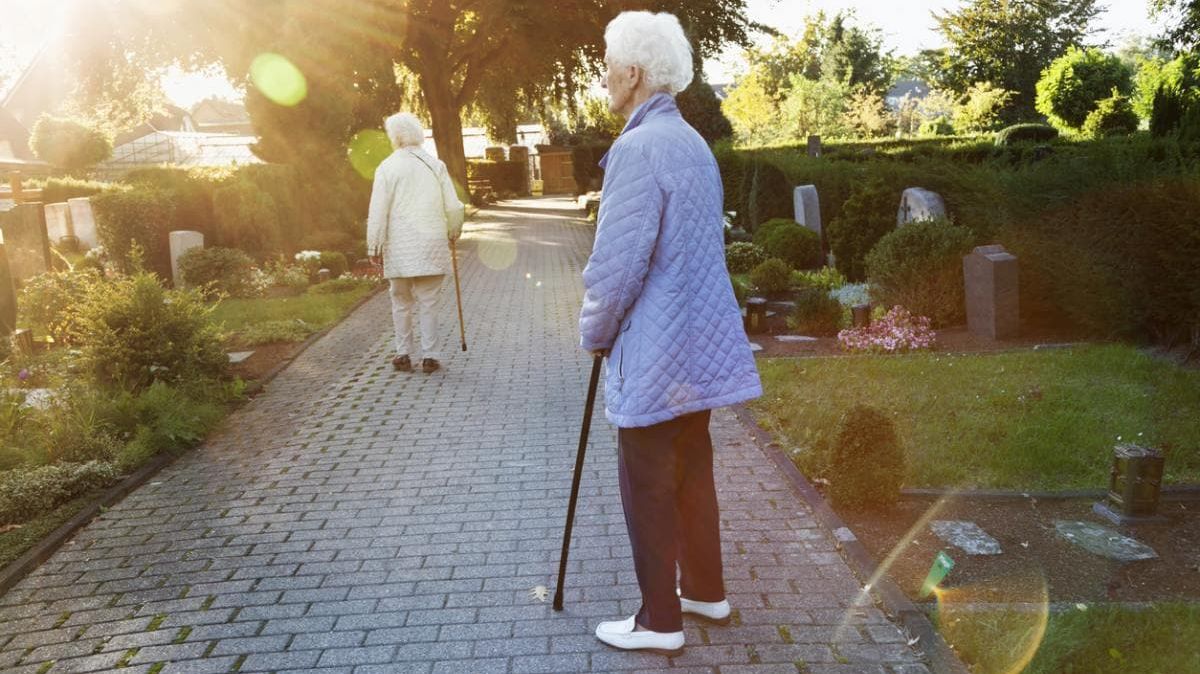 Zwei ältere Damen, die einen Friedhof besuchen.