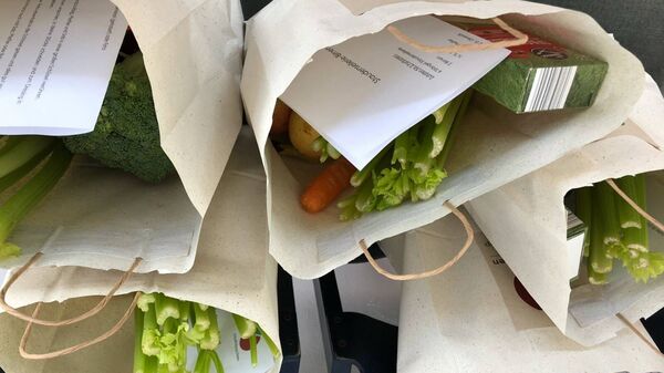 Obstkäppchen-Papiertüten, die mit Gemüse, Obst und einem Rezept gefüllt sind.