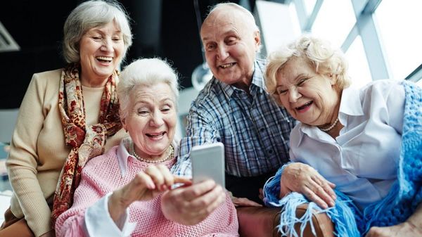 Mehrere Senioren schauen lachend auf ein Smartphone