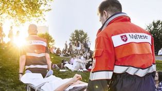 Zwei Mitarbeiter des Malteser Sanitätsdienstes tragen eine Person mithilfe einer Trage.