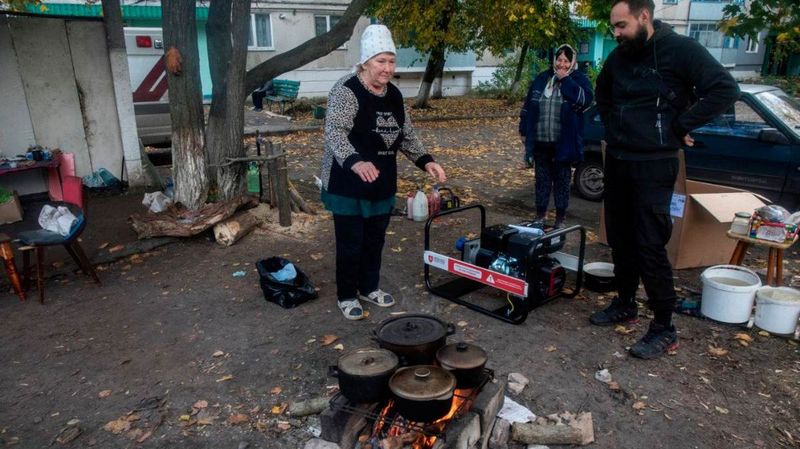 Menschen kochen mit Töpfen über einem Holzfeuer 