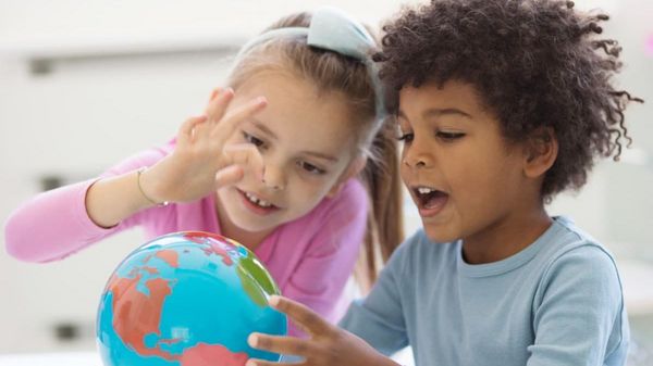 Es werden zwei Kinder gezeigt, welche einen Globus betrachten.