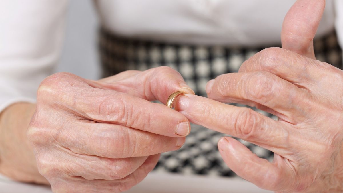 Eine ältere Frau nimmt ihren Ehering ab.
