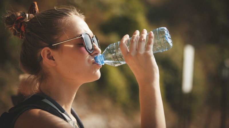Eine junge Frau trinkt aus einer Wasserflasche.