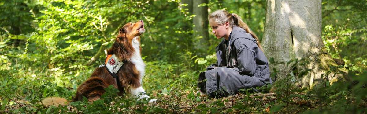 Ein Rettungshund und eine junge Frau in einem Wald