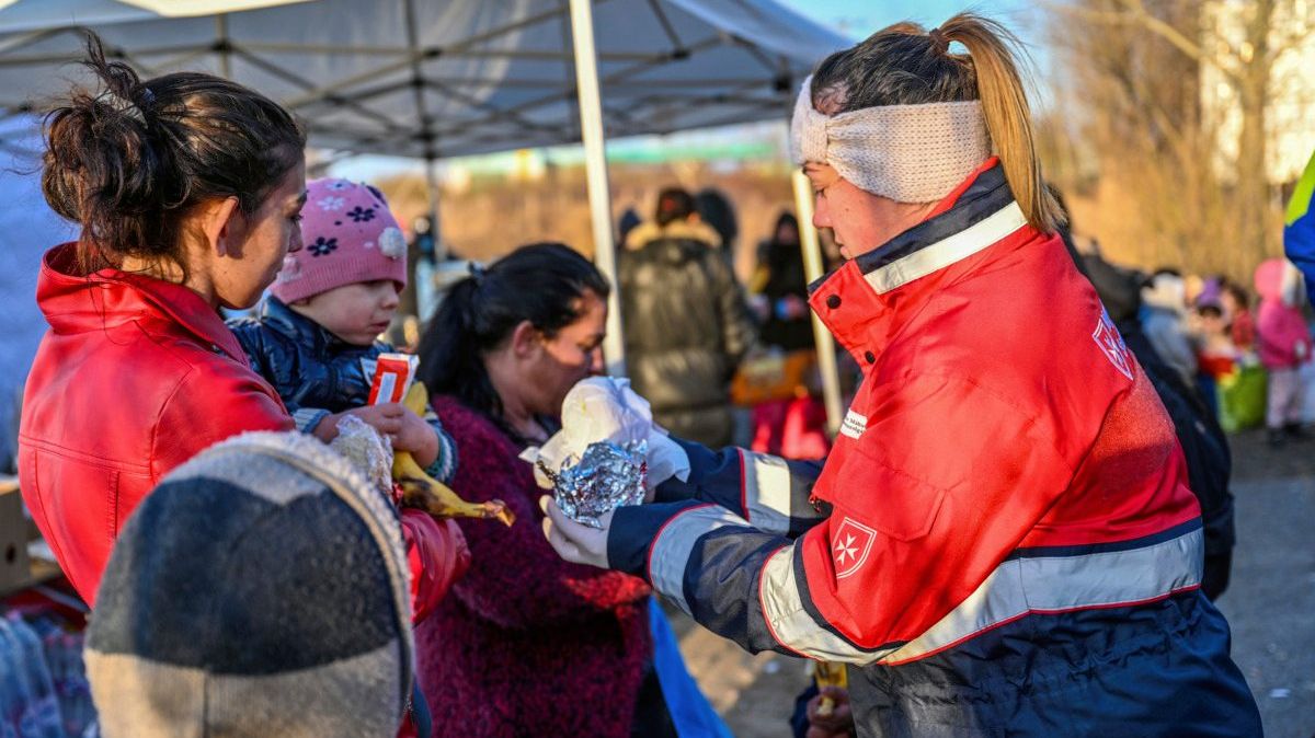 Eine junge Frau verteilt Hilfsgüter an Geflüchtete