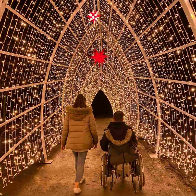 Eine Frau und ein Mann im Rollstuhl in einem Tunnel aus Lichterketten