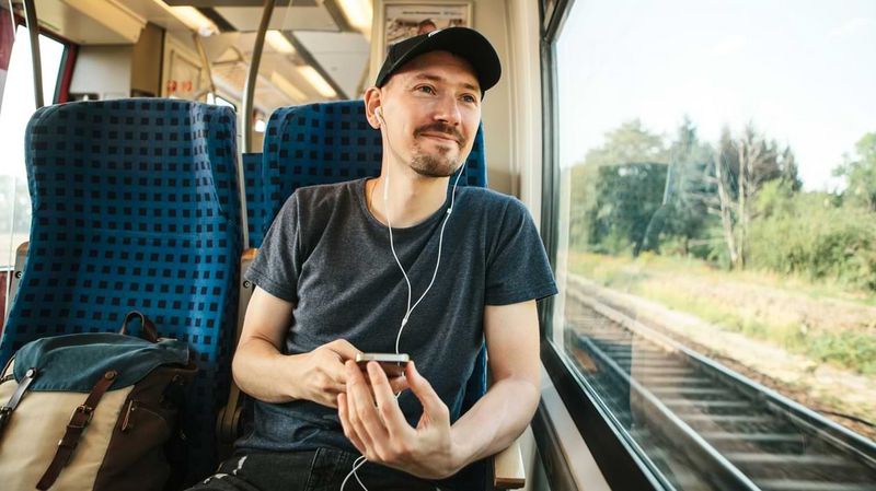 Ein junger Mann mit Kopfhörern in einem Zug
