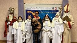 zwei Nikoläuse, vier Engel und ein Mann mit einem Hund auf dem Arm