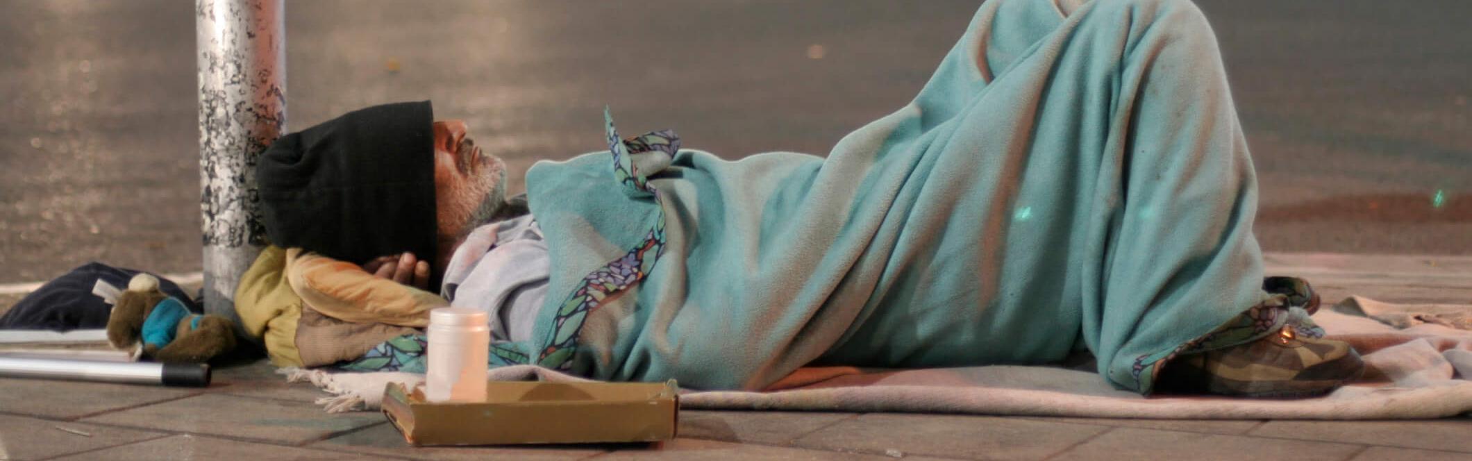 Obdachloser liegt auf dem Bürgersteig