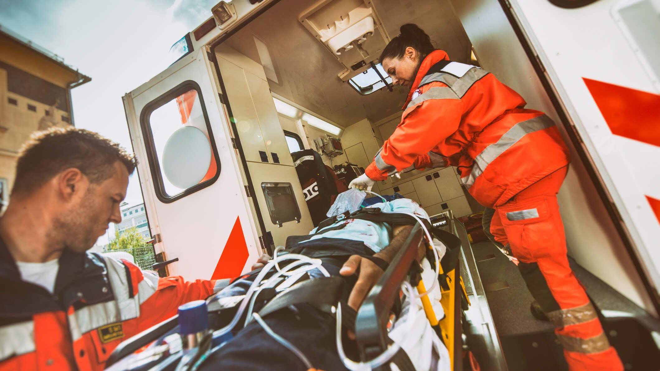 Zwei Rettungssanitäter transportieren einen Patienten in den Rettungswagen
