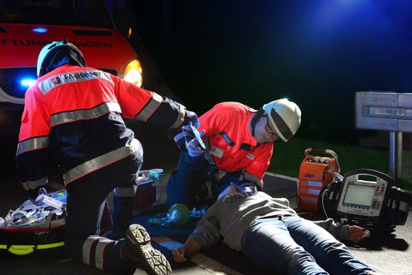 Rettungskräfte der Malteser versorgen einen am Boden liegenden Mann