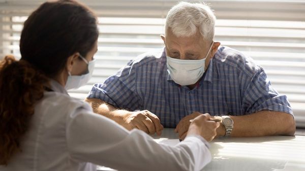 Ein älterer Mann mit Maske wird von einer Ärztin beraten.