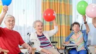Ältere Menschen halten einen Luftballon in die Luft.