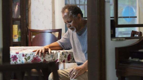 Ein älterer Mann sitzt allein und deprimiert in seinem Wohnzimmer.