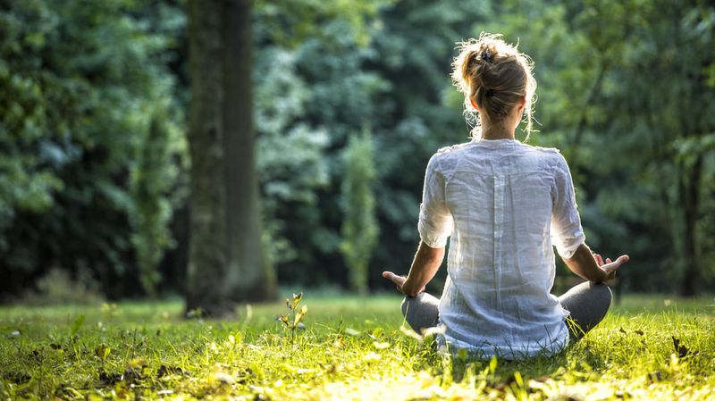 Eine junge Frau meditiert im Wald