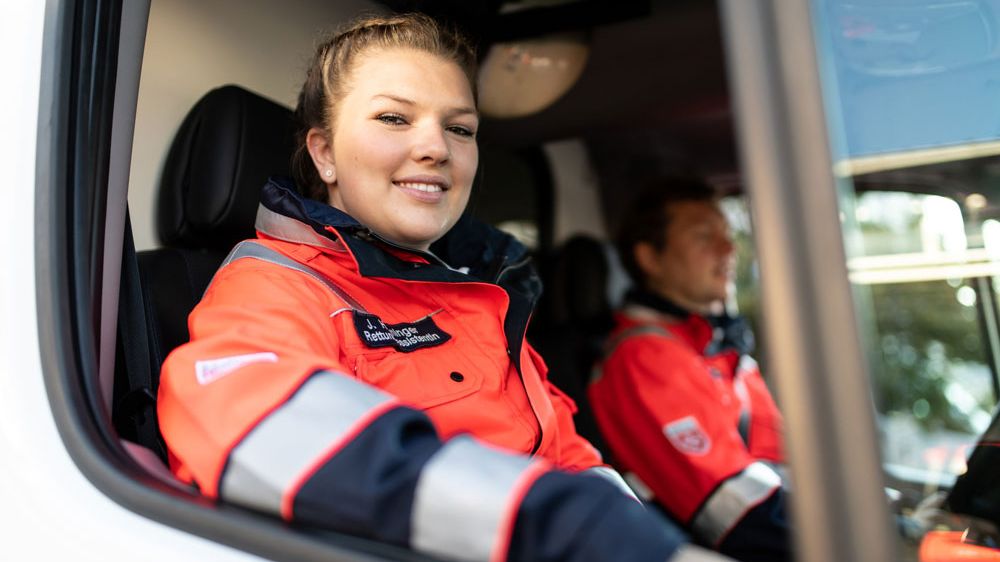 Es wird eine Malteser Notfallsanitäterin aus dem Rettungsdienstwagen gezeigt.