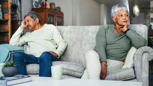 Ein älteres Paar sitzt an entgegengesetzten Enden eines Sofas.